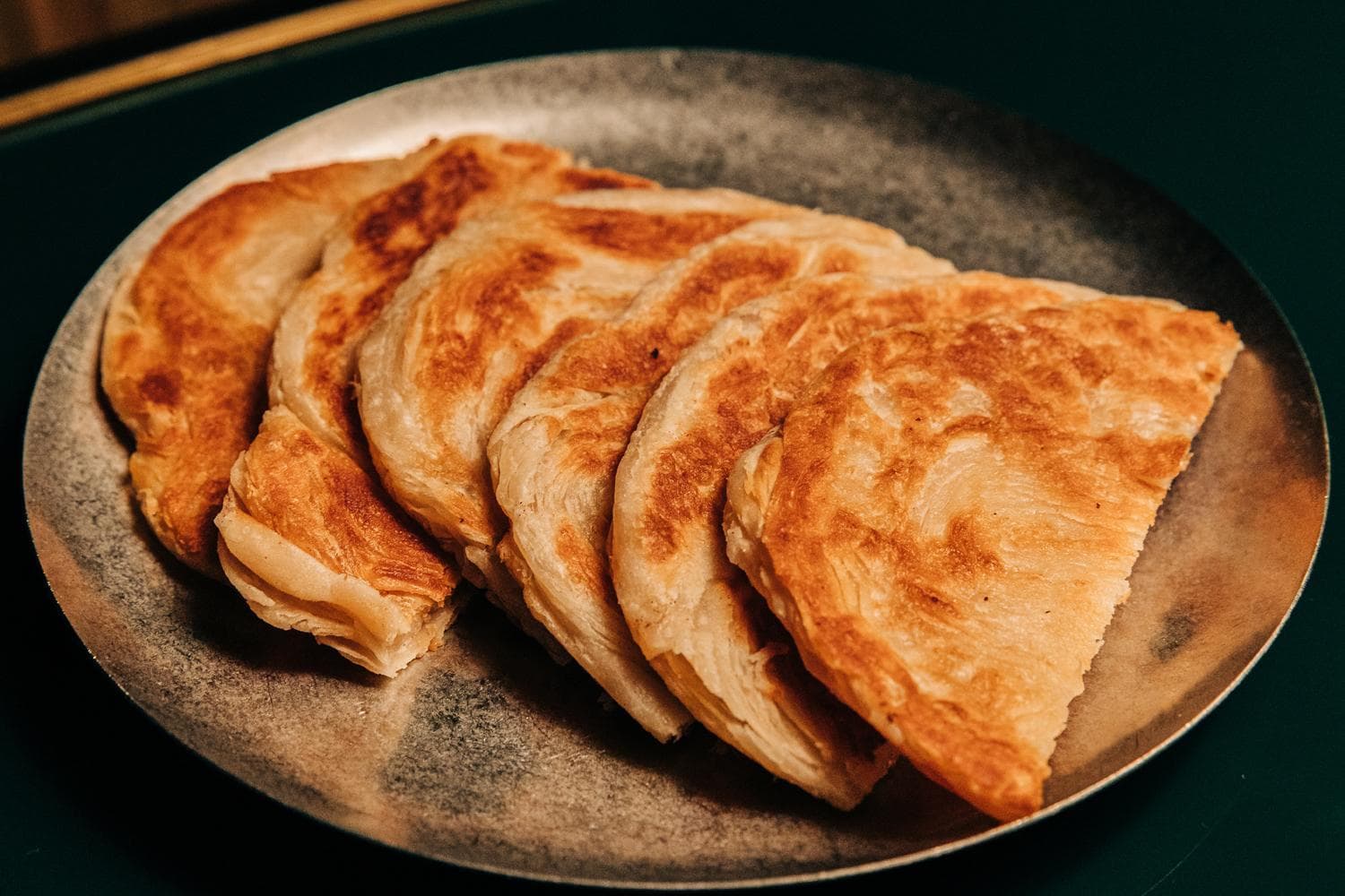 A plate with several pieces of golden-brown, grilled roti arranged neatly.